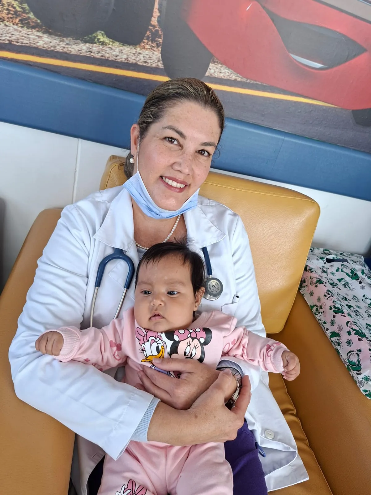 La Dra. Mafe cargando a un bebé en consulta