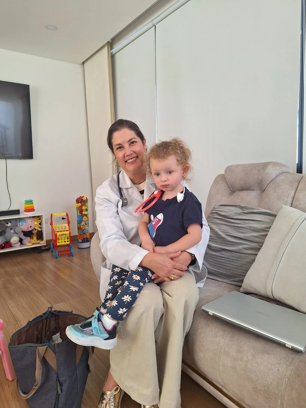 La Dra. Mafe en consulta domiciliaria cargando a una niña pequeña