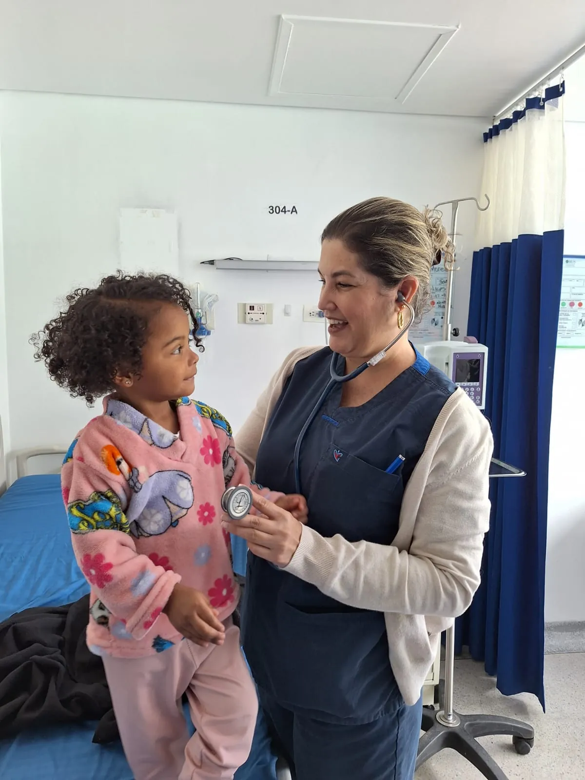 La Dra. Mafe dejando que una niña escuche su estetoscopio en consulta